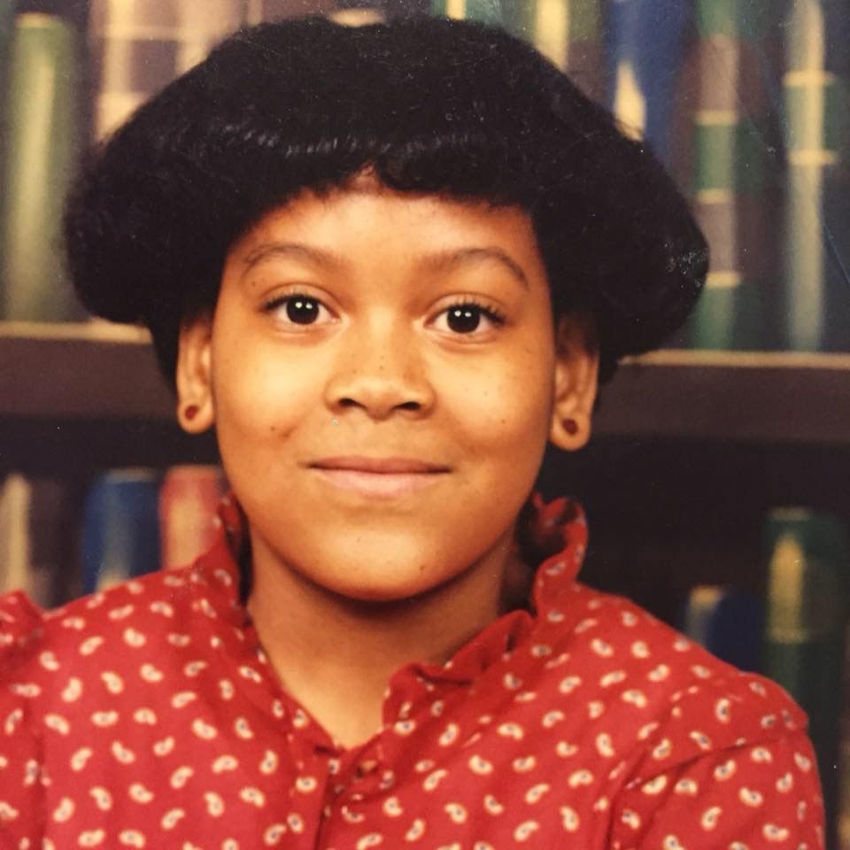 A young girl in a red dress with red earrings

