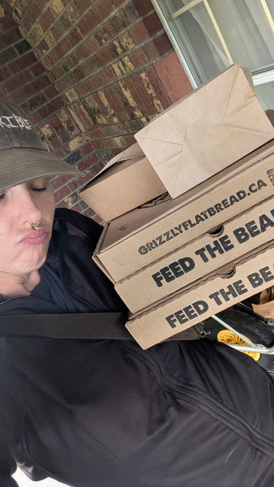 Josie holding 3 pizza boxes from grizzly flatbread 