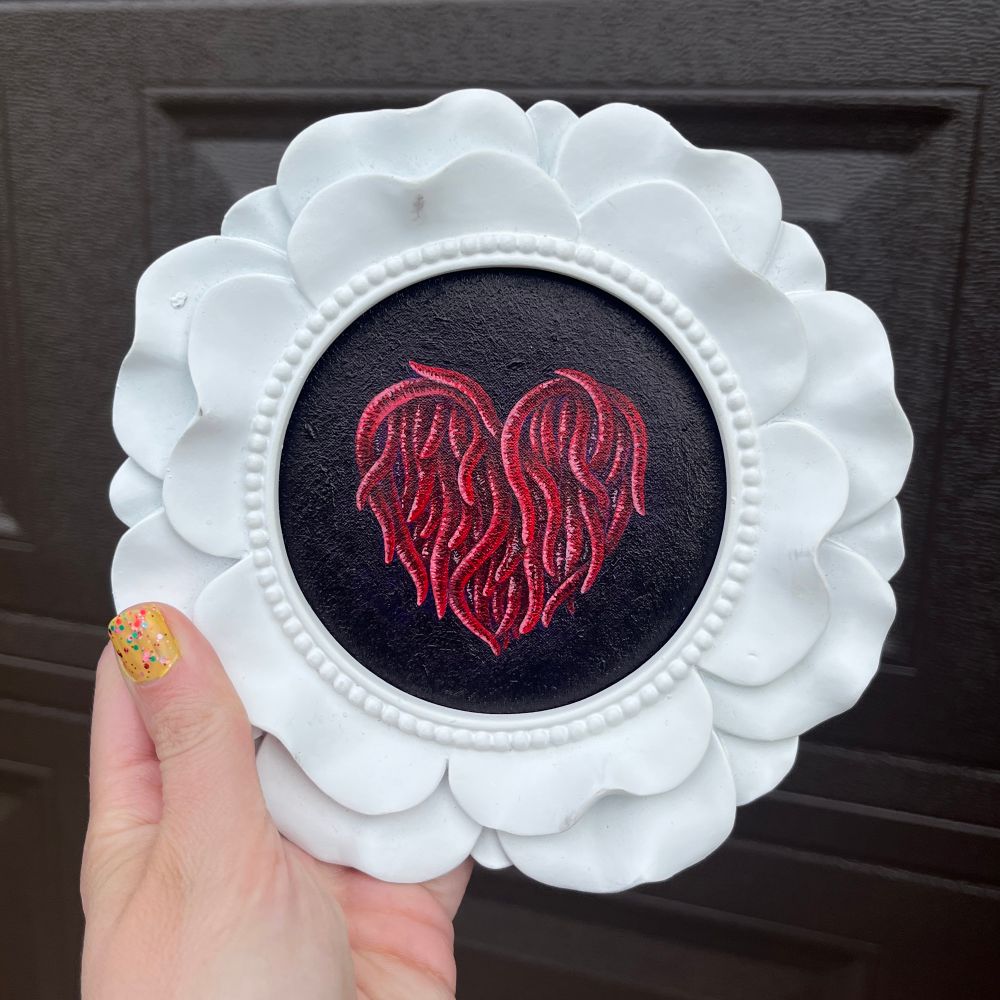 another heartworm painting in a white frame shaped like a flower 