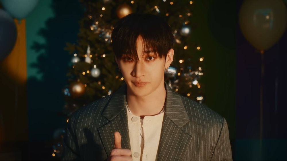 Chan looking to the camera and making a thumbs up with one of his hands. Heβs wearing a white shirt and a dark blazer over it.