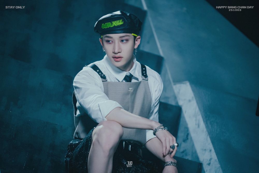 Chan sitting in some stairs, looking away from the camera. One of his arms is resting on his knee.