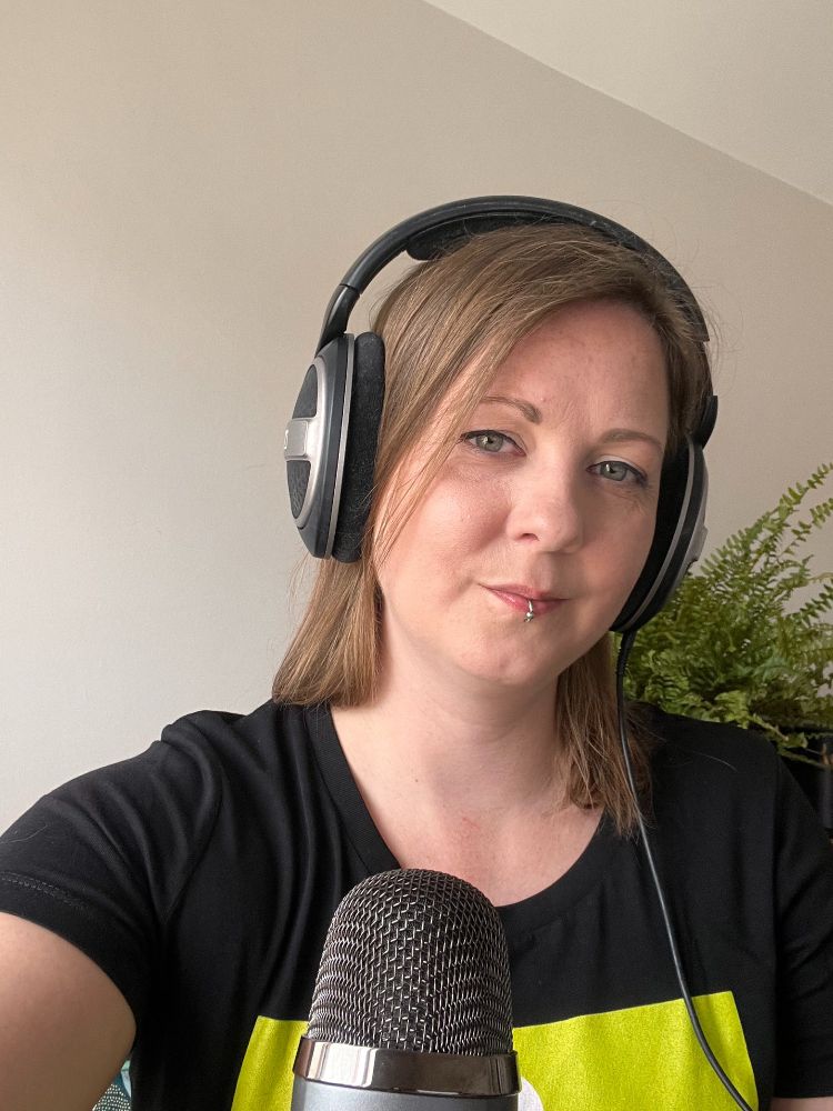 A photo of me wearing headphones, with a microphone in front of me. I'm wearing a black t-shirt with the Robot Talk logo on, which is just visible at the bottom of the frame as a bright green square.