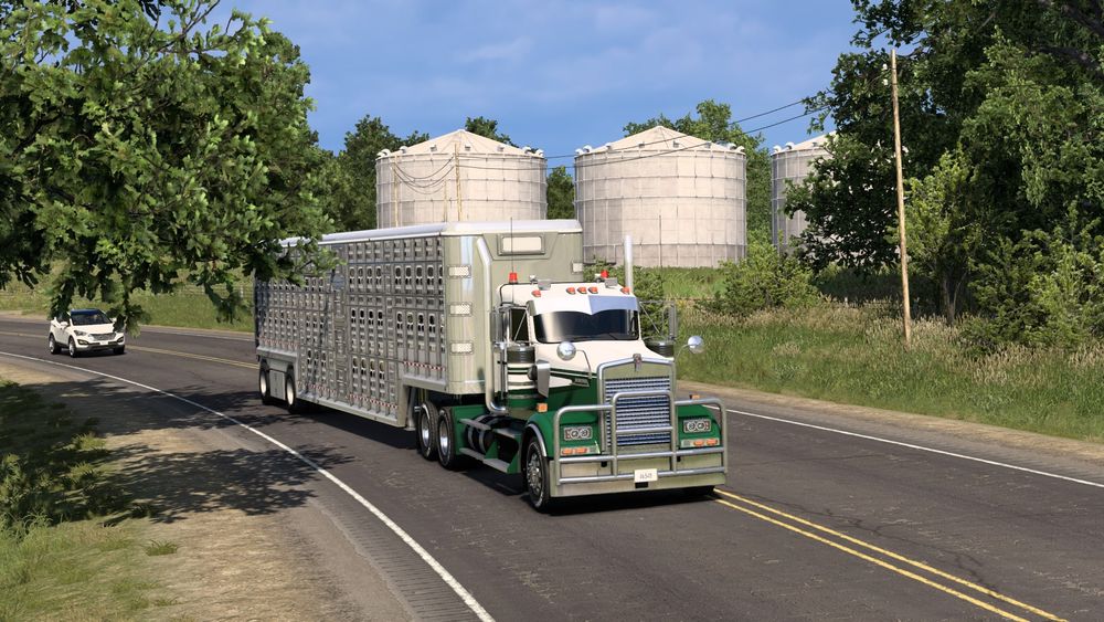 American Truck Simulator screenshot of my Kenworth W900 passing some silos on Route 136.