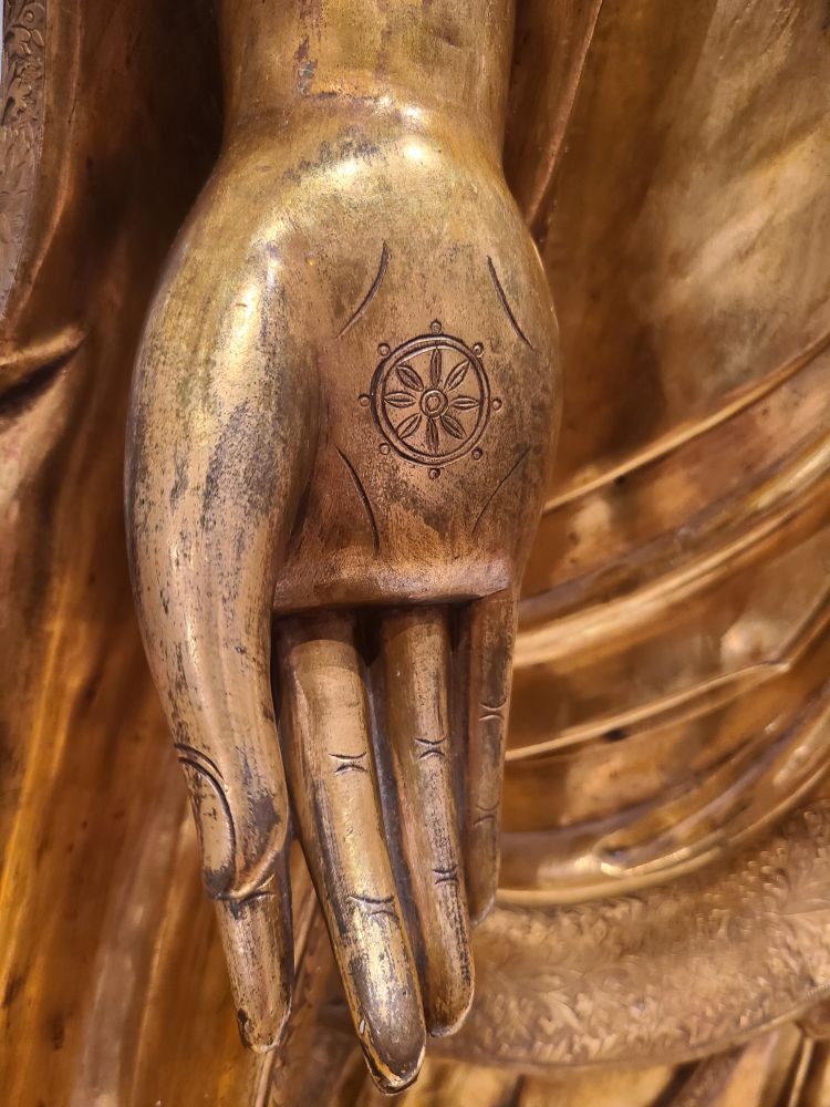 Detail of the hand of a Chinese brass Buddha statue found in the Royal Ontario Musuem. The hand is marked with an 8-spoked wheel for the Noble Eight Fold Path.