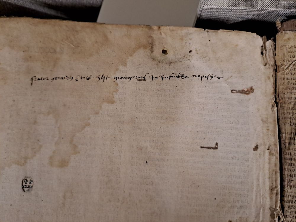Afbeelding van een dekblad in een vijftiende-eeuws boek met een deels onleesbare eigendomsinscriptie.
