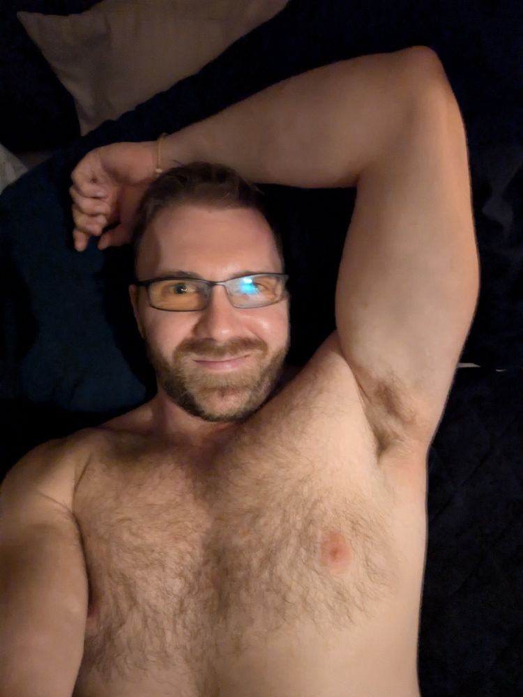 Hairy muscle guy wearing computer glasses with his arm lifted, showing off his armpit 