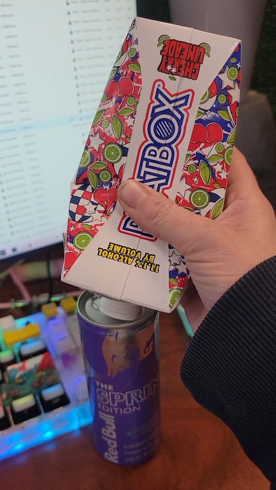 A cherry limeaid 'Beatbox' malt beverage being freshly squeezed into a previously emptied can of grapefruit redbull