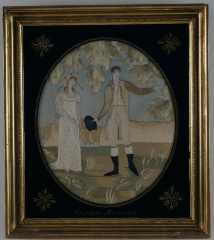 A needlework picture embroidered in silk, with a man in a brown coat and riding boots and a woman in a white gown and straw bonnet standing in front of a wheat field.
