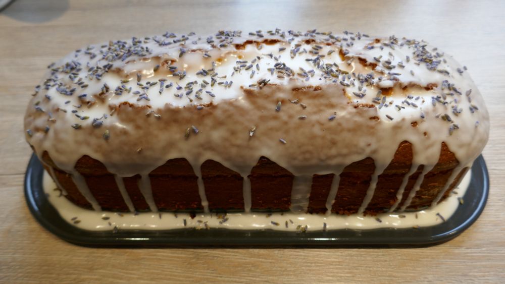 Ein in der Kastenform gebackener Zitronenkuchen, mit Zuckerguss glasiert und mit Lavendelblüten garniert.
