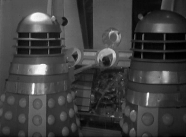Two Daleks looking at a circular screen that shows footage of Susan.