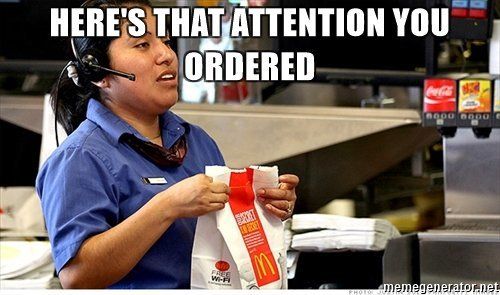 A McDonalds worker holding a bag says "here's that attention you ordered."