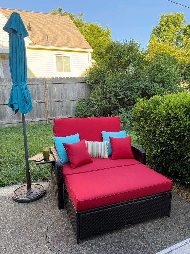 Outdoor loveseat/daybed with red cushions.