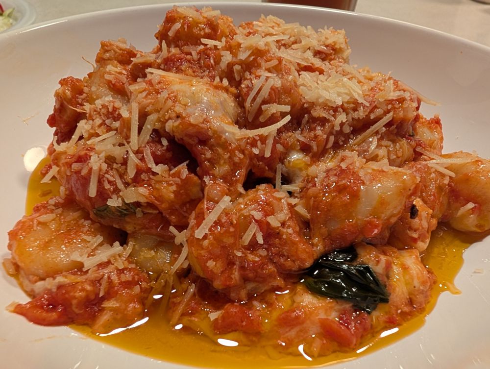 A mound of Gnocchi Alla Sorrentina on a white ceramic dish
 
The gnocchi is piled high, sprinkled with Parmesan cheese on top, and with a small pool of olive oil at the bottom. 

I especially love this dish for being easy, both in making the gnocchi and the sauce of olive oil, garlic, tomatoes, fresh basil, shredded Parmesan, and plenty of fresh mozzarella on top.