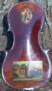 Close up of the back of a 19th century violin with two pieces of decoupage