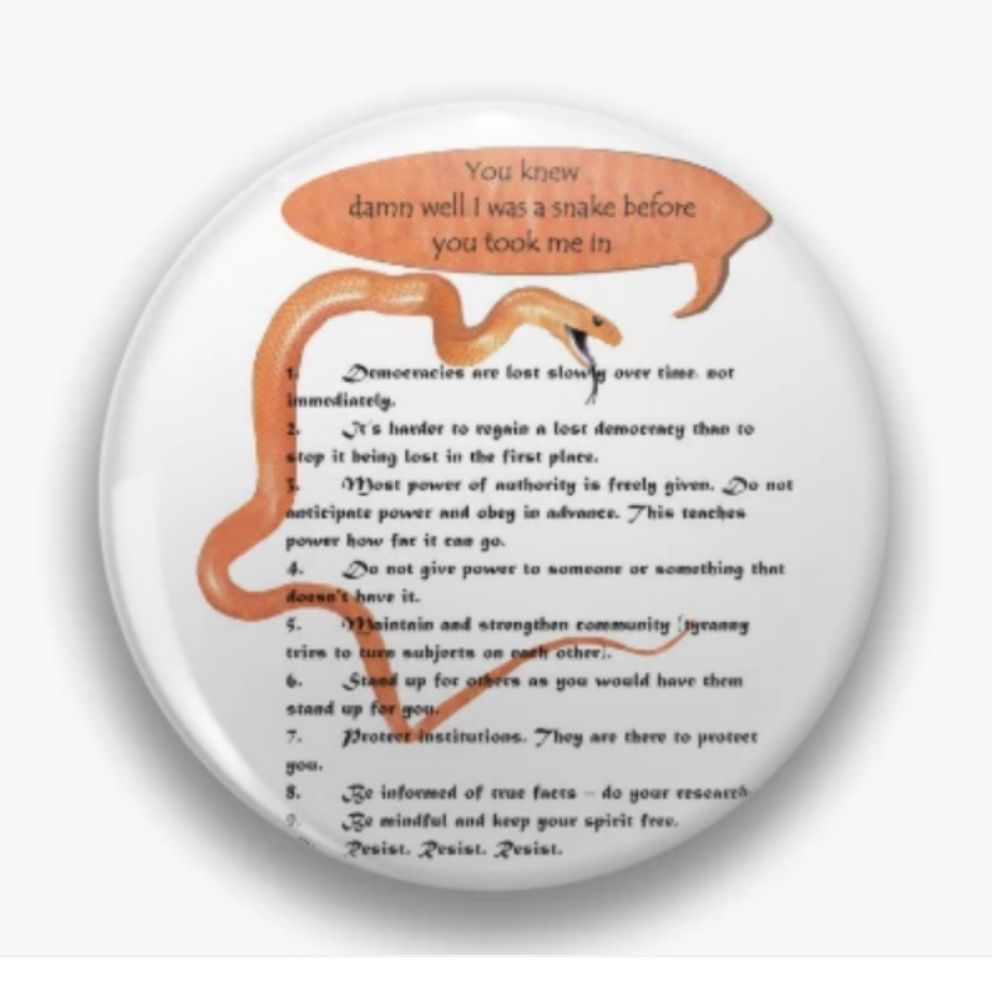 Button badge with the design of an orange coloured Brown Eastern Snake around and through the black stylised text in a numbered list of the rules of how to resist tyranny. Above & coming from, the snake, a matching orange speech bubble containing black text ‘You knew I was a snake before you took me in’.
(design by SnakeTshirts and available on Redbubble)
