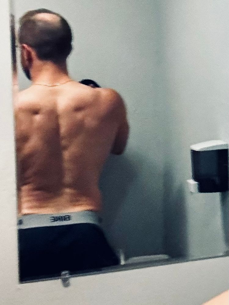 Zoomed in photo of shirtless man’s back in a reflection