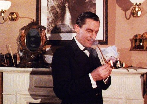 Animated gif of Jeremy Brett as Sherlock Holmes, lighting a pipe in the rooms of Baker Street 