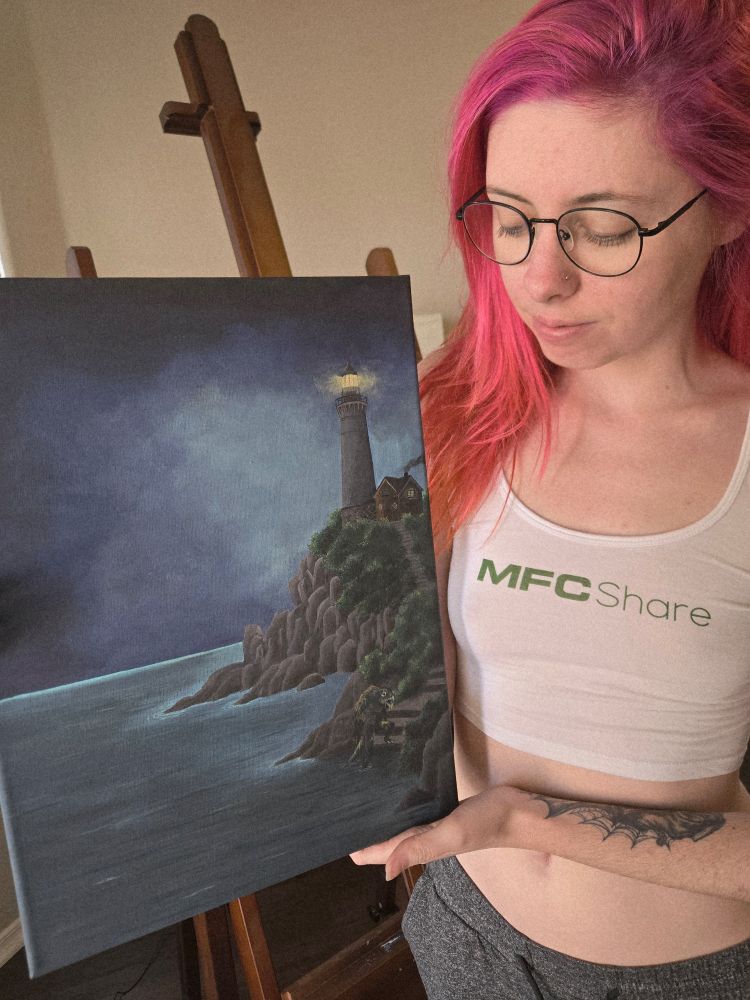 Eluna holding the painting described in the first photo. She is wearing a white crop top that says MFC share, she has pink hair and glasses