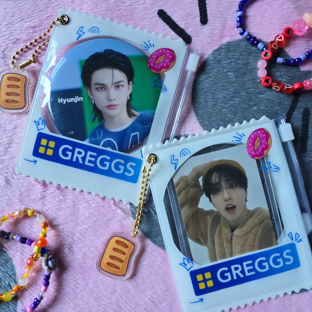 A photocard holder that has the Greggs logo on it and a little sausage roll charm hanging from it.