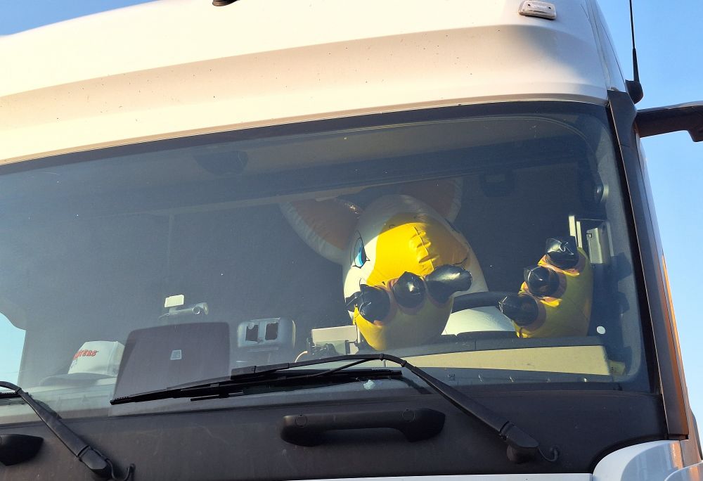A pooltoy gryphon sitting behind the semi-trucks wheel. 
