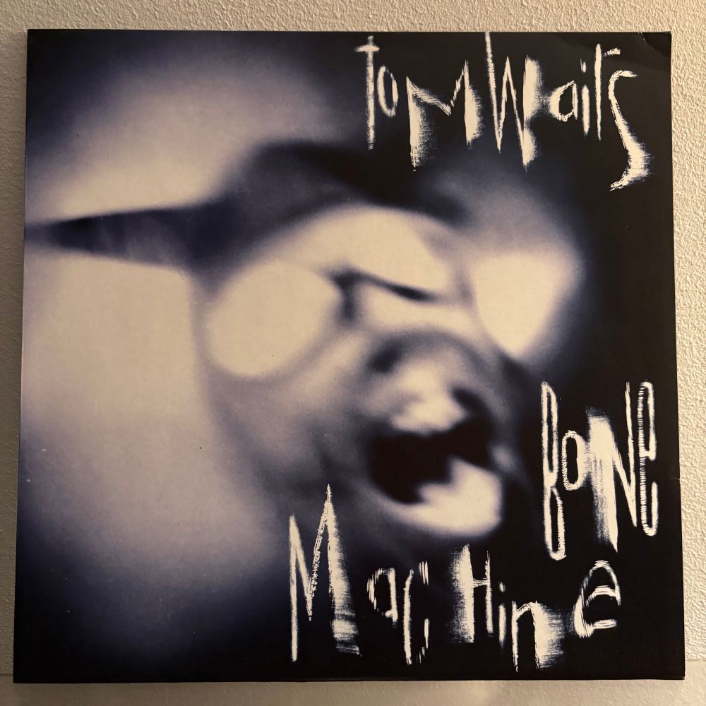 Tom Waitsin Bone Machinen LP:n mustavalkoisessa, sinitoonatussa kannessa sarvipäinen hahmo suu auki.