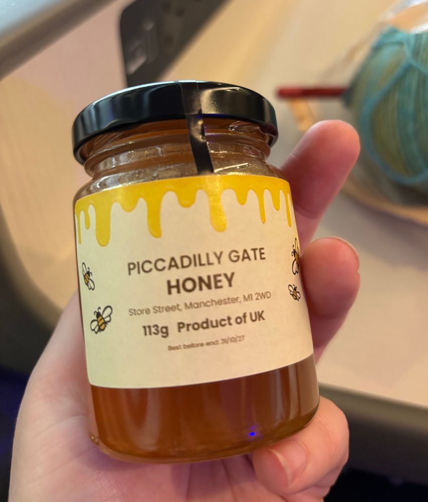 Hand holding a little jar of honey branded ‘Piccadilly Gate’
