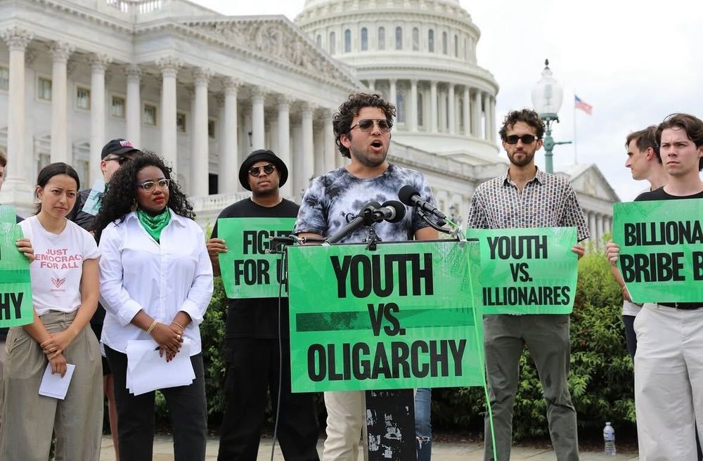 photo of a Get Free activist speaking in front of the US Capital Building with the sign "Youth vs. Oligarchy"