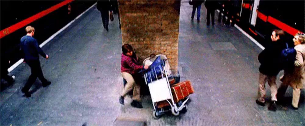 a man pushing a cart with boxes on it in a subway station .