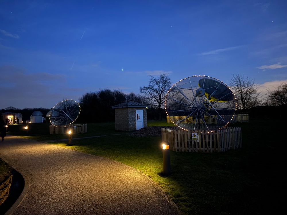 Two radio telescopes, with lights around the edges of the dishes 