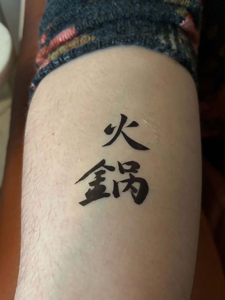 white woman's inner forearm with 火锅 temporarily tattooed on