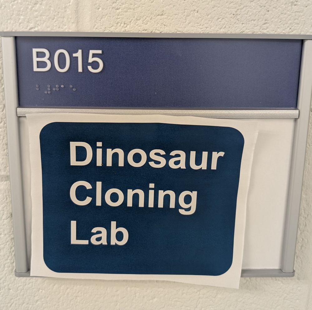 Blue sign with white text that reads "dinosaur cloning lab" 