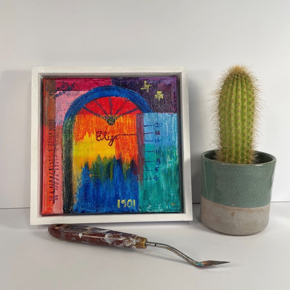 Square Georgian door colourful abstract painting with a small cactus in a pot beside it and a palette knife in front of it 