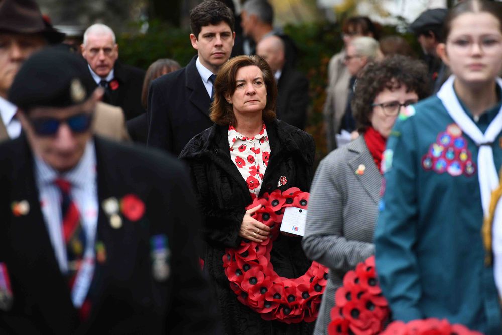 Group of people including the First Minister standing solemnly holding red poppy wreaths during a Remembrance Sunday service at the Cenotaph in Cardiff.