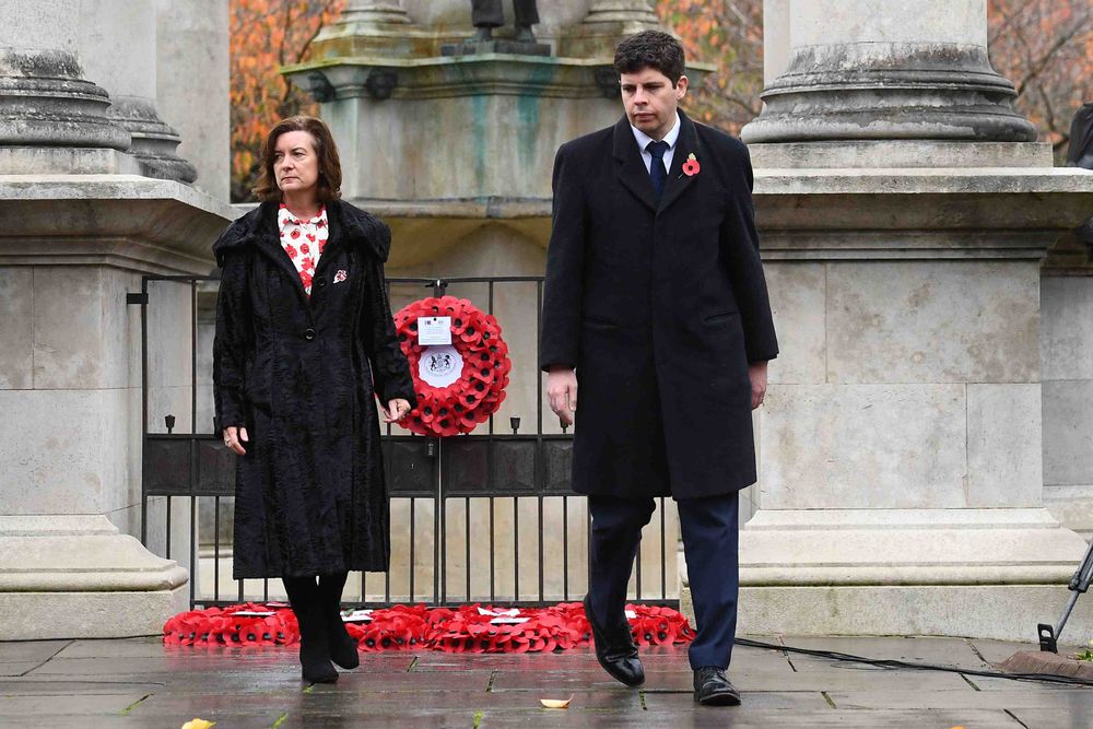The First Minister and a colleague in dark coats walking back from laying a red poppy wreath at the Cenotaph memorial in Cardiff.