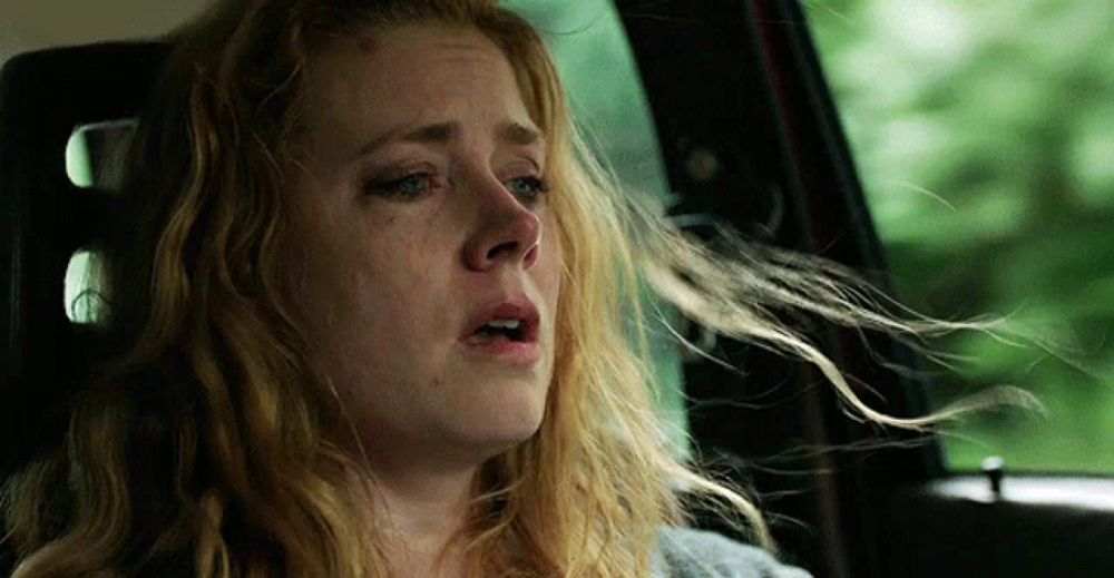 a woman is sitting in the back seat of a car with her hair blowing in the wind