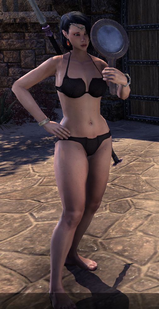 Before you stands a woman, wearing little more than black underwear, posing with one hand on her hip, the other holding up a hand-mirror, in which she studies her reflection.