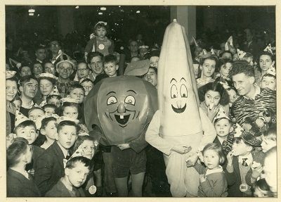 Black and white photograph of children at a Christmas party with two people in costume dressed as Alfie Apple and Bertie Banana. Taken at Price's tailors, Leeds, 1946. Collections of Leeds Museums and Galleries.

Alfie Apple was a daily cartoon in the Leeds Mercury (later in the Yorkshire Post) written by "Aunty Joan" and illustrated by Thack from the 1930s to 1950s