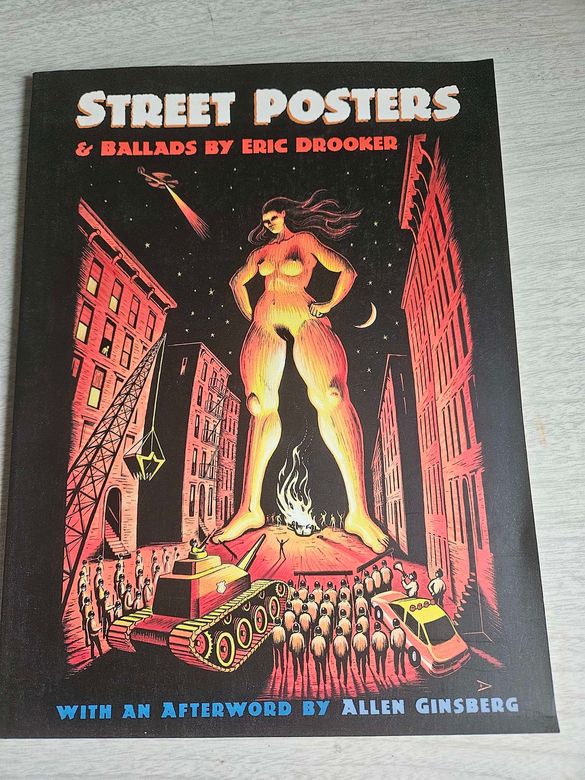 image of the cover of Eric Drooker's book "Street Posters." A graphic novel style rendition shows a powerful, giant naked woman standing, towering over a street in New York, facing off against a tank, a policecar, a wrecking crane and a phalanx of police. It is rendered in oranges and yellows as she is lit by a fire from below. The fire light reveals dancing protesters. Behind her is a night sky with stars and crescent moon.