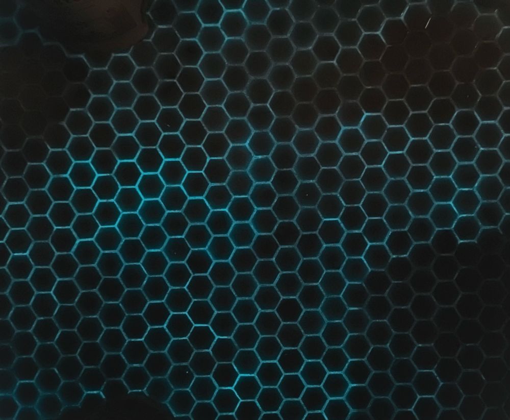 1” hex tile outlined by luminescent, faintly green grout lines. 

I cannot convince the phone to unsharpen those lines its frantically autocorrecting because they seem less sharp due to internal reflections in the irridescent tile. 

The floor looks more evenly “glowy” than this making it look like walking on clouds from eye level. 

The dark spots are where the squatty potty was blocking the light that charged it up 😬
