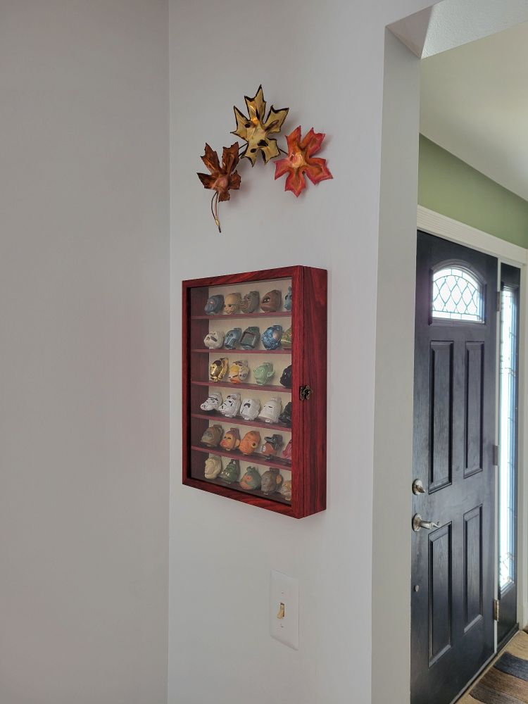 A curio cabinet hangs on a wall on the other side of the foyer