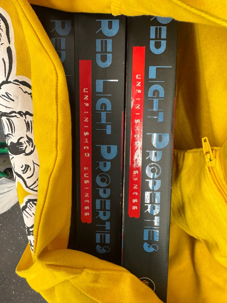 Yellow tote bag is open to show copies of slipcase edition RED LIGHT PROPERTIES graphic novels