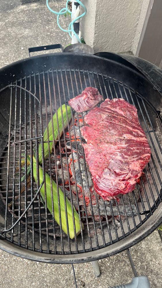A Wagyu Bavette on a Webber kettle over direct heat. There's ears of corn tucked up next to the coals