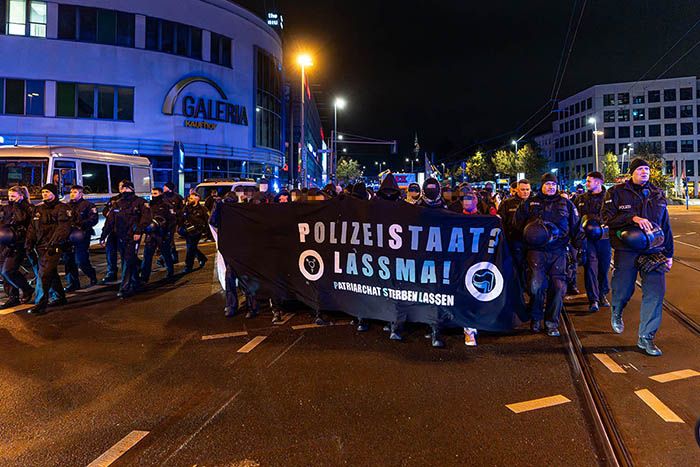 "Polizeistaat? Lassma! Patriarchat sterben lassen". Demoteilnehmer*innen mit Leittransparent auf der abendlichen Demonstration am 25.10.2025 in Berlin, umgeben von einem Polizeispalier.