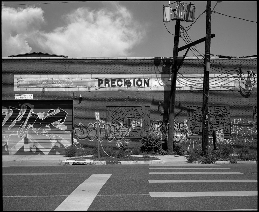 Looking across the street, the sign on a building says Precision, but ironically, the S in precision is crooked and falling. 