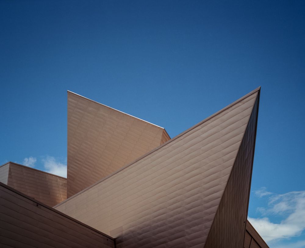 Looking up at the Denver Art Museum, the geometric shapes constructed of titanium sharply stand out against a bright blue sky. 