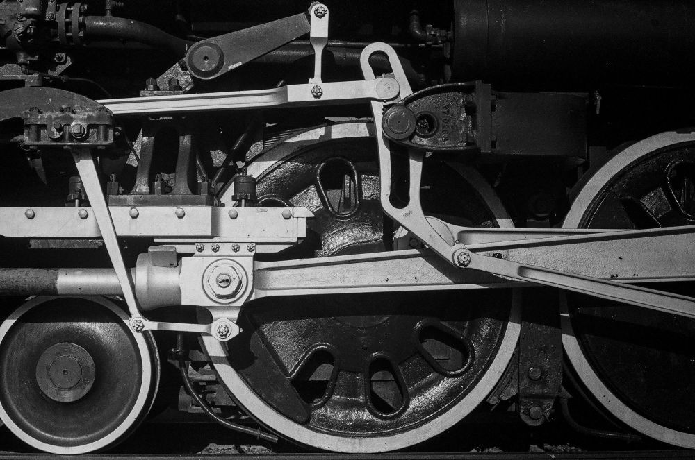 A close-up of the Frisco Meteor 4500 steam engine driving wheels in black and white. Dramatic light brings out the highlights of the metallic silver paint around the wheels and the coupling rods against the deep black of the other heavy metal parts. The Frisco Meteor steam engine has been restored and is permanently parked at Tulsa’s Route 66 Historical Village Train and Depot.