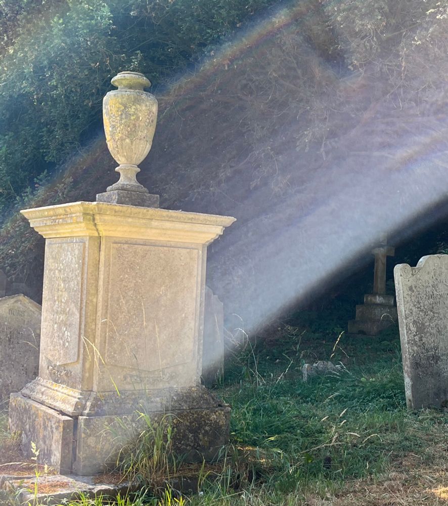 Tomb in churchyard lit by sunrays.