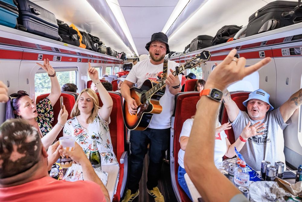 Oasis fans singalong on an LNER train with hands in the air 