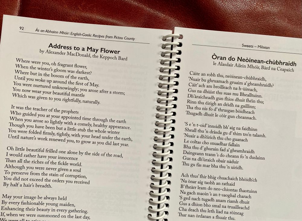 A cropped 2-page spread from a Gaelic-English cookbook published by Bradan Press, with the English on the left and the Gaelic on the right. It's a Gaelic poem, "Òran do Neòinean-chùbhraidh" which means "Address to a May Flower". 