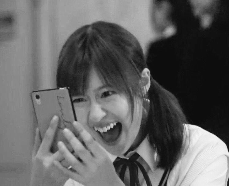 black and white photo of a girl looking at her phone and freaking the fuck out